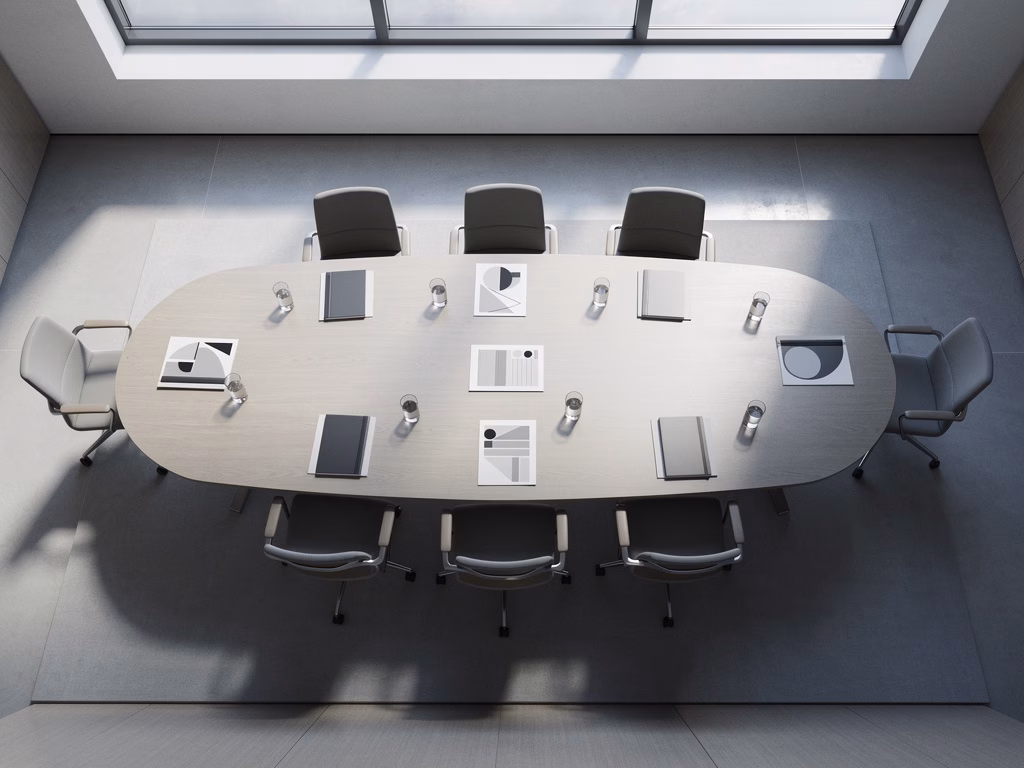 Empty modern conference room seen from above with a large oval table, notebooks, and water glasses arranged symmetrically