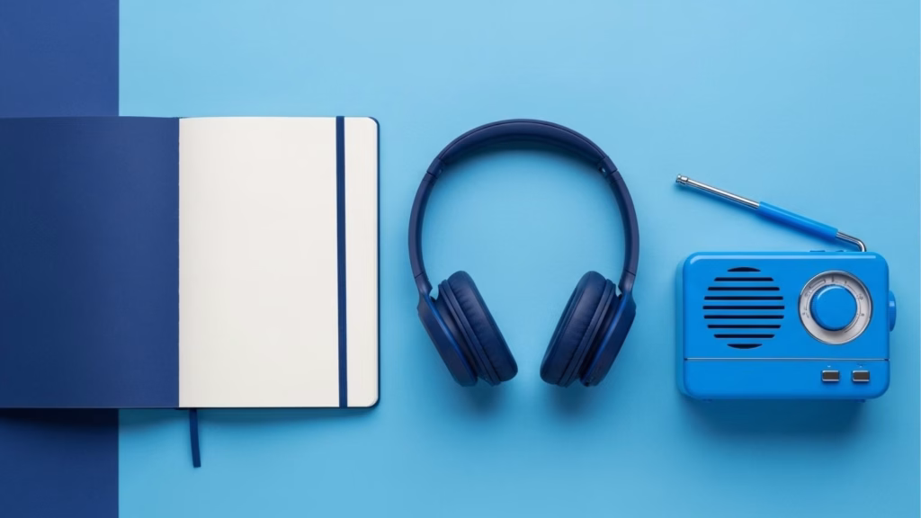 Caderno aberto, fone de ouvido e rádio azul sobre fundo em tons de azul.